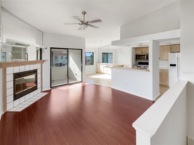 unfurnished living room with a tile fireplace, dark hardwood / wood-style floors, ceiling fan, and lofted ceiling