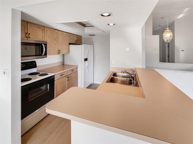 kitchen with pendant lighting, white appliances, sink, a textured ceiling, and kitchen peninsula