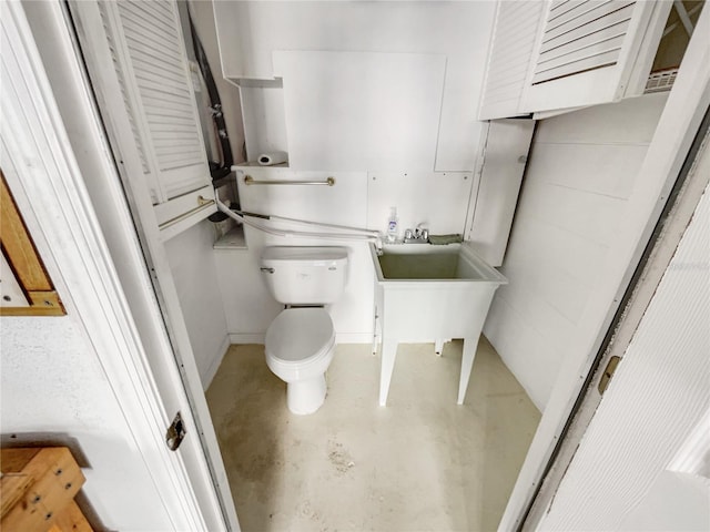 bathroom with concrete flooring and toilet