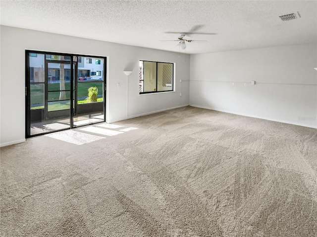 unfurnished room featuring ceiling fan, carpet floors, a healthy amount of sunlight, and a textured ceiling