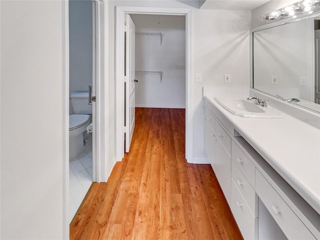 bathroom with vanity, toilet, wood-type flooring, and a textured ceiling