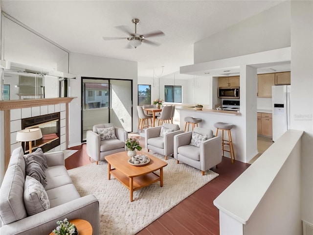 living room with ceiling fan, lofted ceiling, a fireplace, and dark wood-type flooring