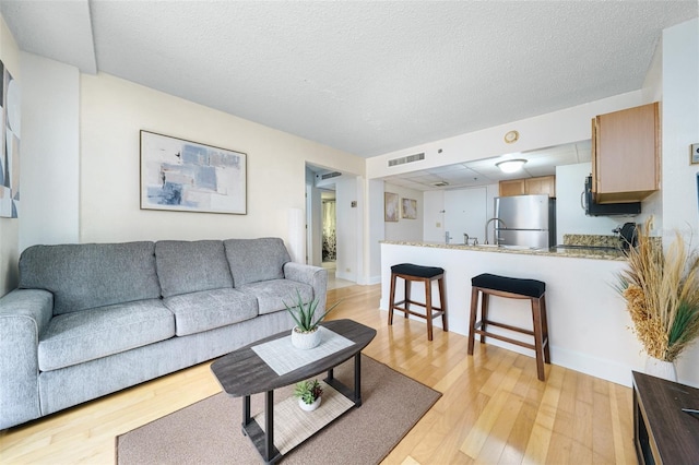 living room featuring light wood-type flooring and a textured ceiling