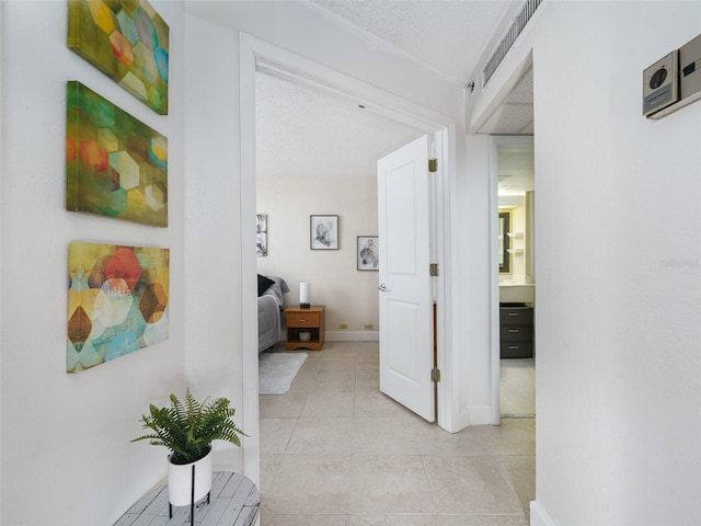 hall with light tile patterned floors and a textured ceiling