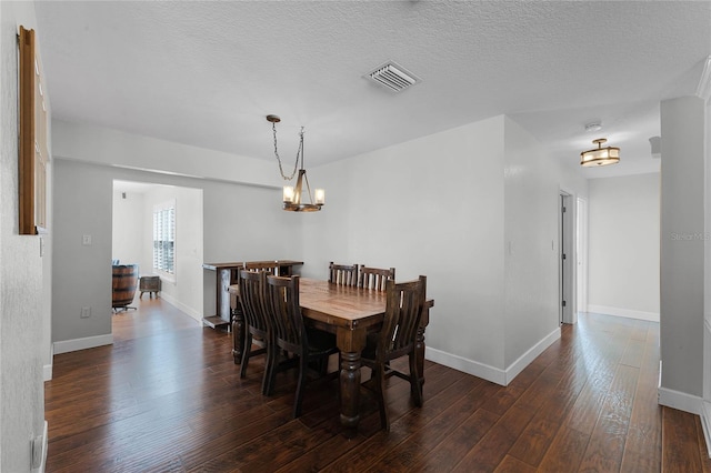 dining area with dark hardwood / wood-style flooring, a textured ceiling, and a chandelier