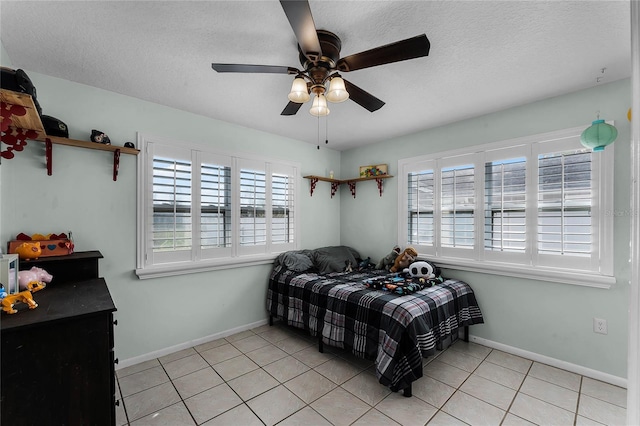 bedroom featuring ceiling fan, a textured ceiling, and light tile patterned floors