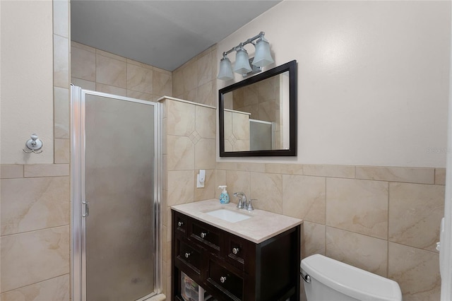 bathroom featuring a shower with door, vanity, tile walls, and toilet