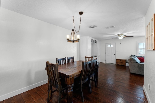 dining room with dark hardwood / wood-style flooring, ceiling fan with notable chandelier, and a textured ceiling