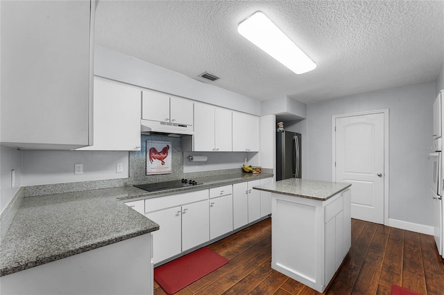 kitchen featuring stainless steel refrigerator, white cabinetry, a center island, black electric stovetop, and a textured ceiling