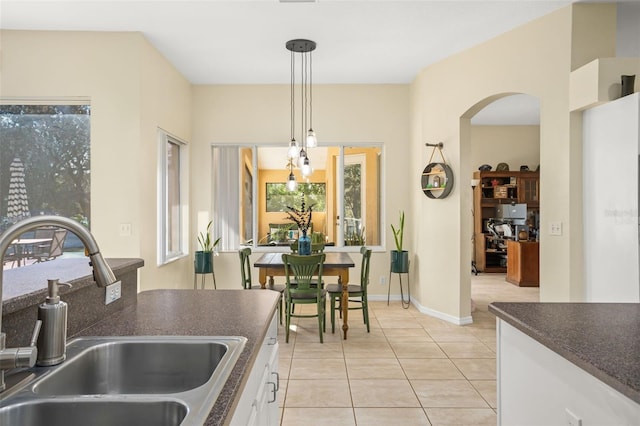 kitchen featuring white cabinets, decorative light fixtures, light tile patterned flooring, and sink