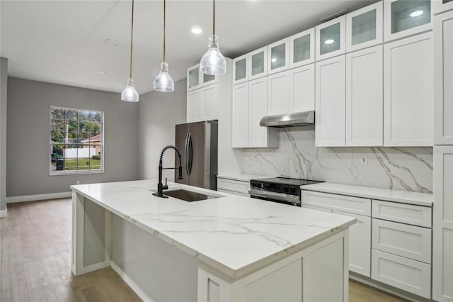 kitchen with light stone countertops, white cabinetry, tasteful backsplash, a kitchen island with sink, and appliances with stainless steel finishes