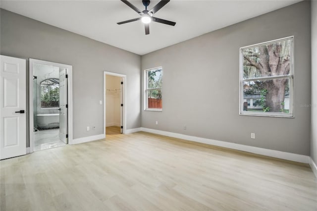 unfurnished bedroom with a walk in closet, ensuite bath, ceiling fan, light hardwood / wood-style floors, and a closet