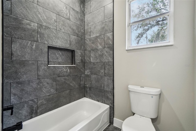 bathroom featuring tiled shower / bath combo and toilet