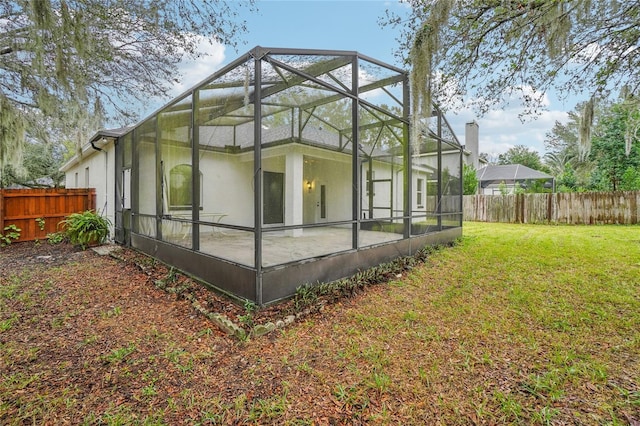 rear view of property featuring glass enclosure and a yard