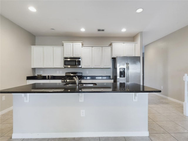 kitchen with a kitchen breakfast bar, an island with sink, and appliances with stainless steel finishes