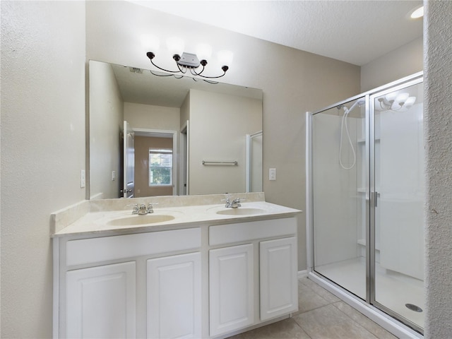 bathroom with tile patterned flooring, vanity, a chandelier, and a shower with shower door