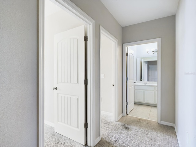 hallway featuring light carpet and sink