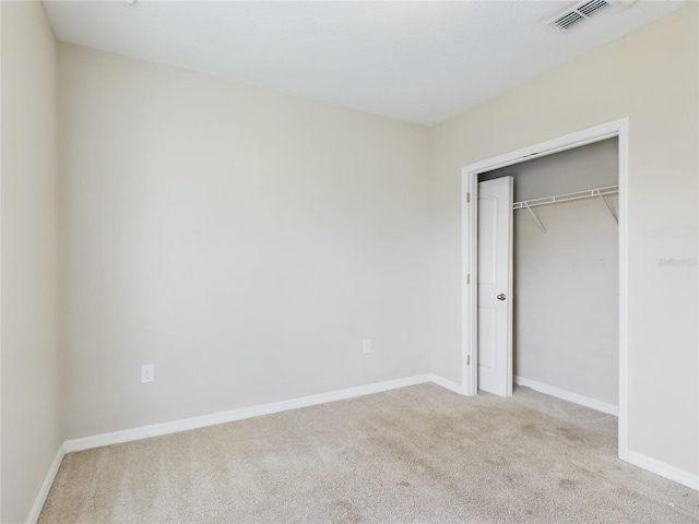 unfurnished bedroom with light carpet and a closet