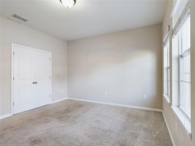 carpeted empty room with a textured ceiling and plenty of natural light