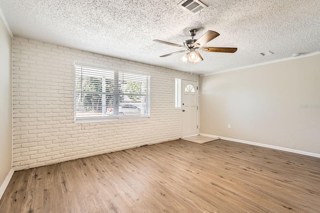 spare room featuring brick wall, a textured ceiling, and hardwood / wood-style flooring