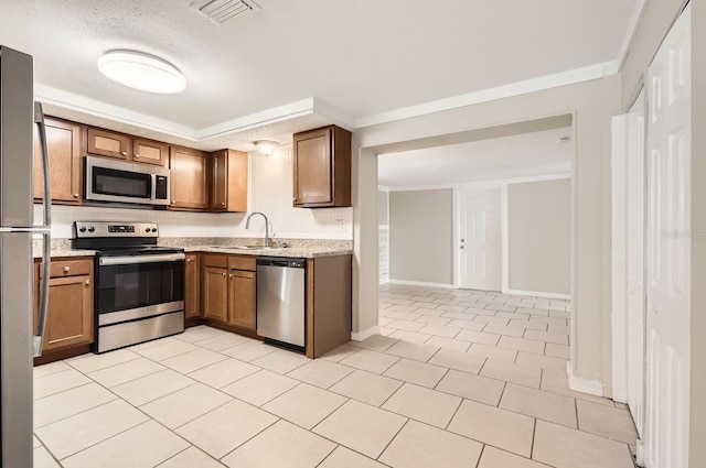 kitchen with sink, stainless steel appliances, crown molding, a textured ceiling, and light tile patterned flooring