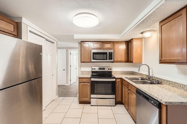 kitchen featuring sink, light tile patterned flooring, a textured ceiling, and appliances with stainless steel finishes