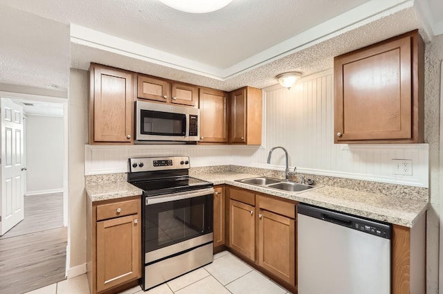 kitchen featuring a textured ceiling, light tile patterned flooring, sink, and stainless steel appliances