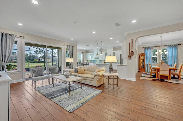 living room featuring a notable chandelier, light wood-type flooring, and crown molding