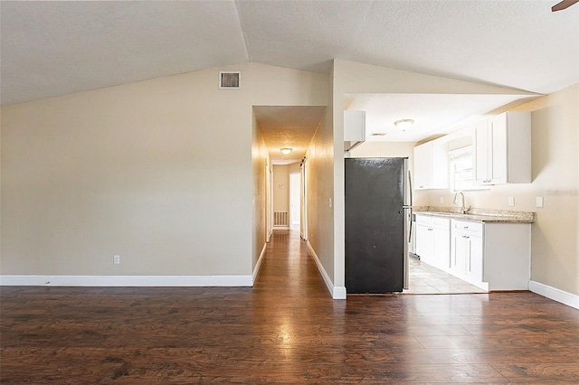 kitchen with dark hardwood / wood-style flooring, white cabinets, stainless steel refrigerator, and vaulted ceiling