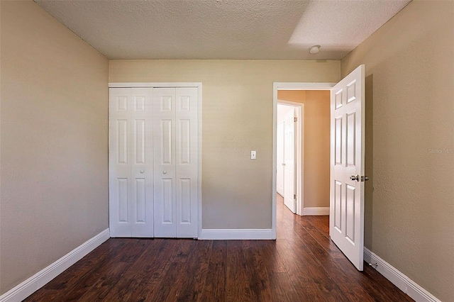 unfurnished bedroom featuring a textured ceiling, a closet, and dark hardwood / wood-style flooring