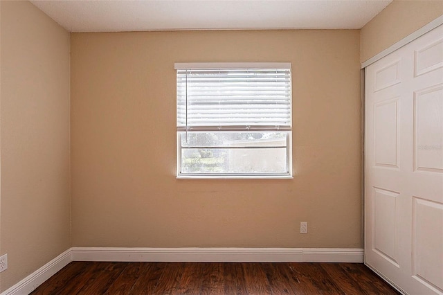 unfurnished room featuring a healthy amount of sunlight and dark wood-type flooring