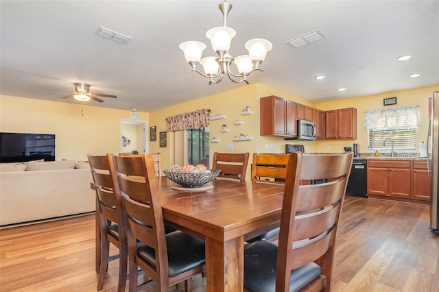 dining area with ceiling fan with notable chandelier, light wood-type flooring, and sink