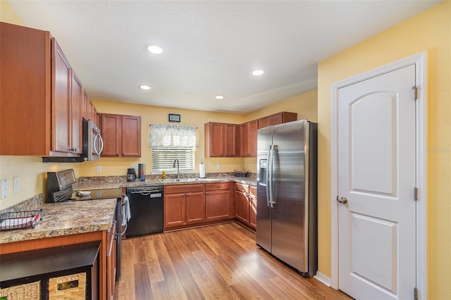 kitchen featuring light stone countertops, sink, black appliances, and light wood-type flooring