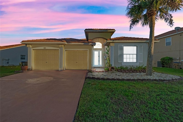 mediterranean / spanish-style home with a garage and a yard