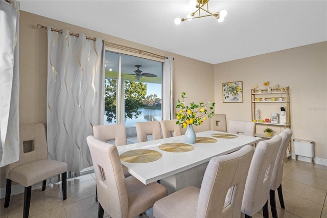 tiled dining space with a notable chandelier and a water view