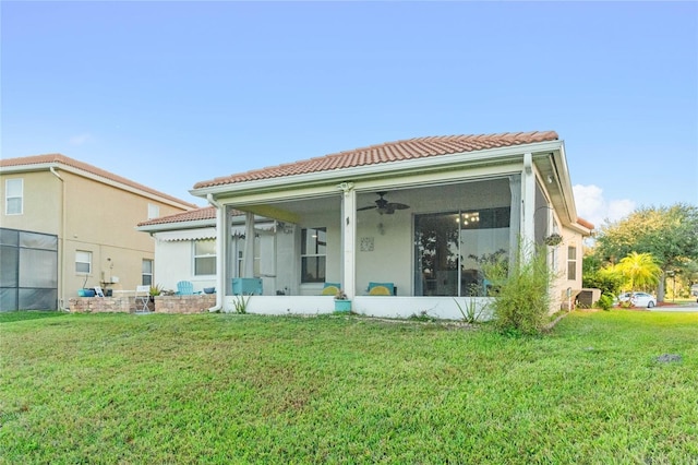 rear view of house featuring a yard, a sunroom, and ceiling fan