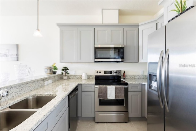 kitchen with light stone countertops, appliances with stainless steel finishes, gray cabinetry, sink, and decorative light fixtures