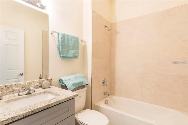 full bathroom with vanity, tiled shower / bath combo, and toilet