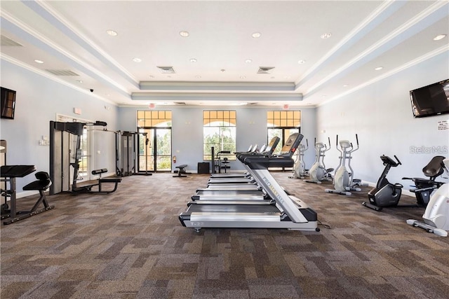 gym featuring a towering ceiling, a raised ceiling, and ornamental molding