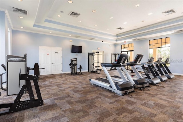 gym featuring a tray ceiling and ornamental molding