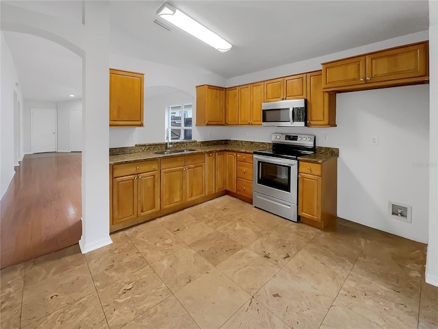 kitchen featuring dark stone countertops, sink, and appliances with stainless steel finishes