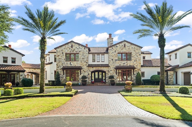 mediterranean / spanish-style home featuring a front lawn and french doors