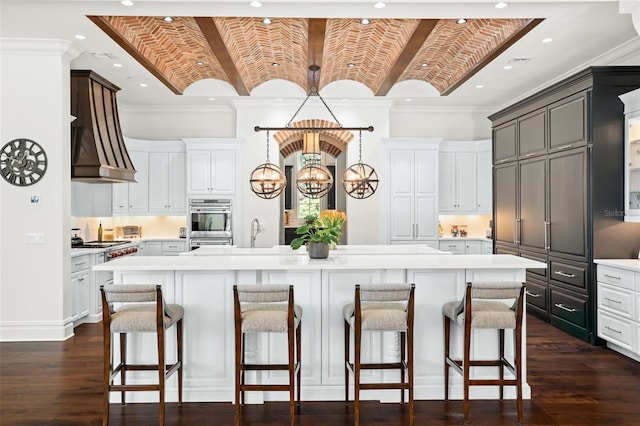 kitchen featuring a large island with sink, white cabinets, hanging light fixtures, a notable chandelier, and brick ceiling