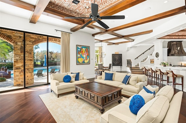 living room with light wood-type flooring, brick ceiling, ceiling fan with notable chandelier, beamed ceiling, and plenty of natural light