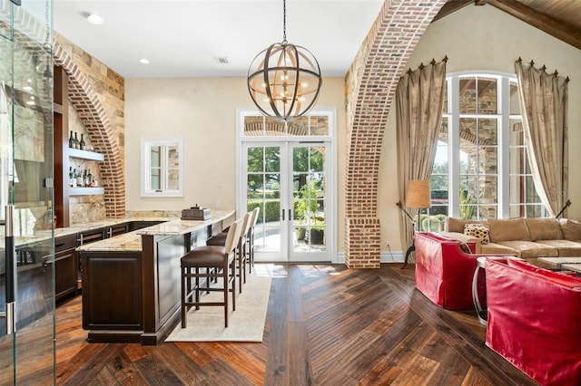 bar featuring french doors, decorative light fixtures, a notable chandelier, light stone counters, and dark brown cabinets