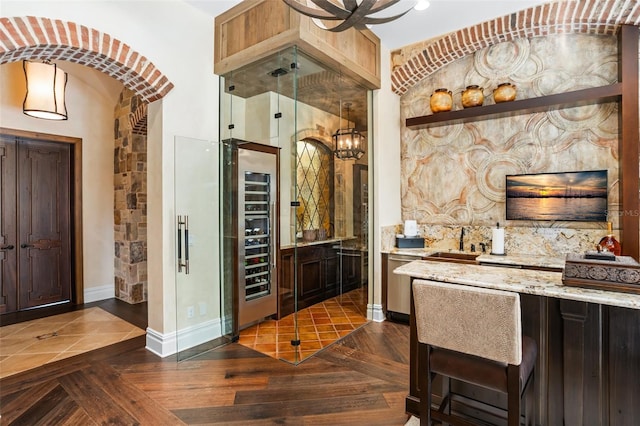 bar with tasteful backsplash, light stone counters, dark parquet floors, sink, and wine cooler