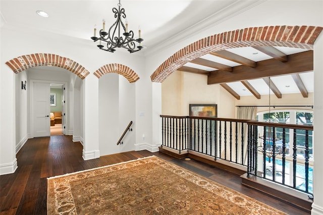 hall with lofted ceiling with beams, dark hardwood / wood-style flooring, and an inviting chandelier