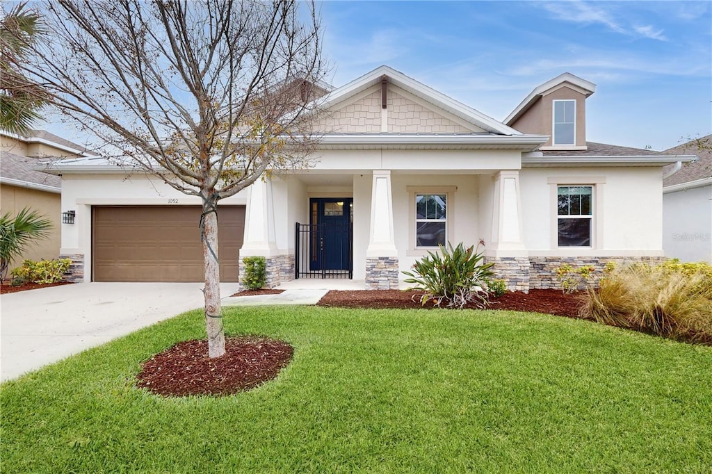 view of front of property featuring a front yard, a garage, and a porch