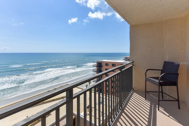 balcony featuring a view of the beach and a water view