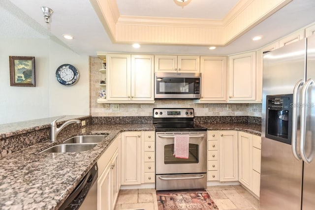 kitchen with cream cabinetry, sink, appliances with stainless steel finishes, and a tray ceiling